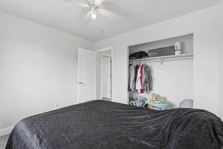 Bedroom featuring a ceiling fan with light fixture, light gray walls, and wood-finish flooring
