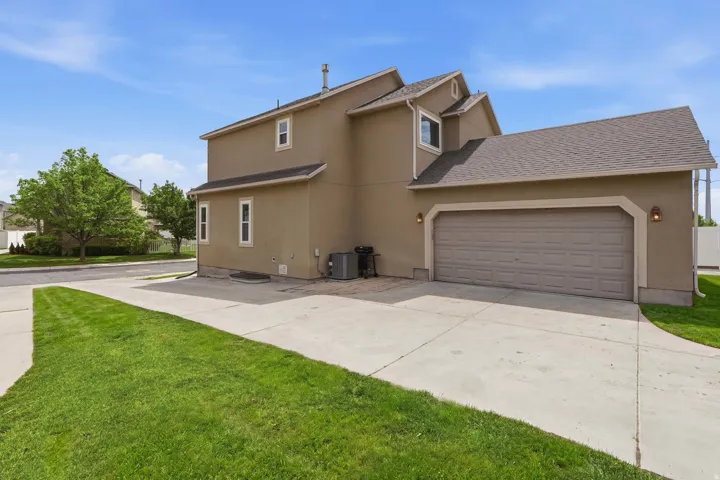 Two-story property featuring a tan stucco exterior, an attached garage, and a concrete driveway