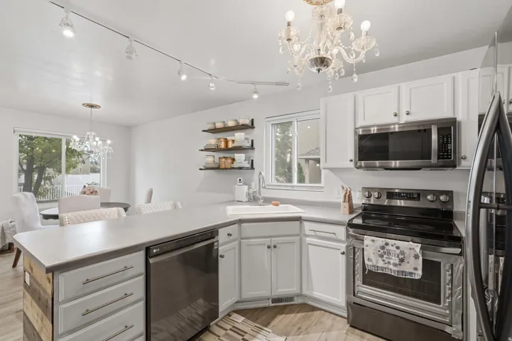 Kitchen featuring white cabinetry, light countertops, stainless steel appliances, and wood-finish flooring