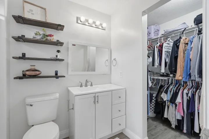 Bathroom featuring a white vanity with integrated sink, chrome faucet, and overhead bar lighting