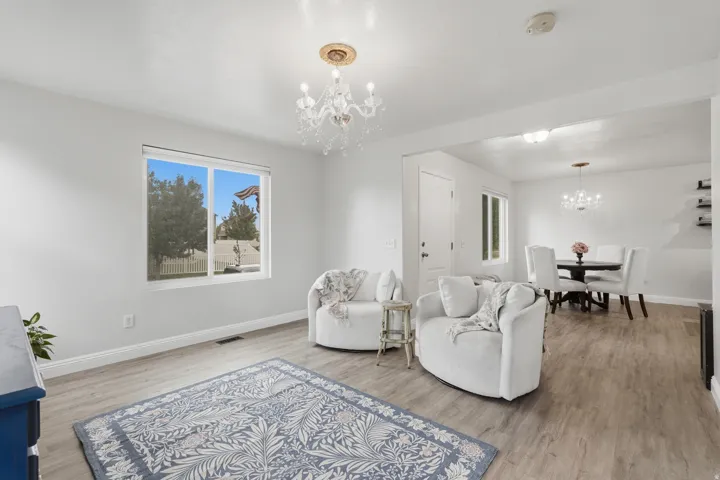 Spacious living area featuring wood-finish flooring, a contemporary chandelier, and a large window