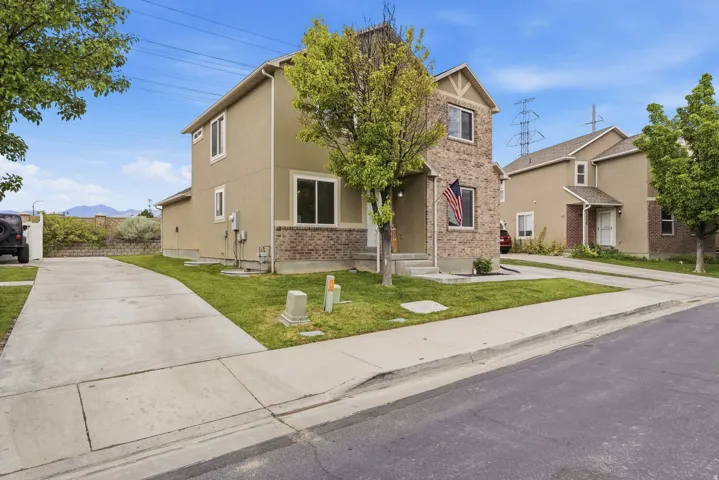 Two-story stucco and brick-veneer exterior with a front entry, multiple windows, and a concrete driveway
