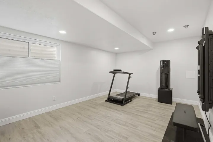 Spacious room featuring light wood-finish flooring, recessed lighting, and a window with a cellular shade