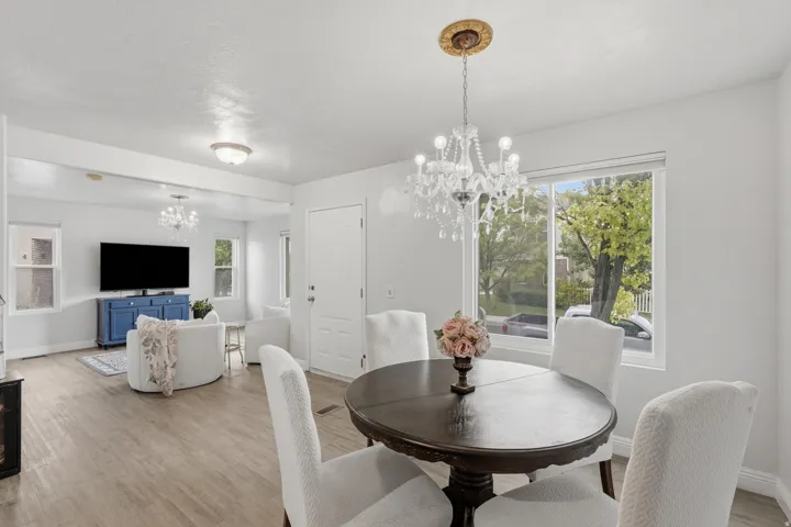 Open-concept living space featuring wood-finish flooring, a decorative chandelier, and abundant natural light from multiple windows