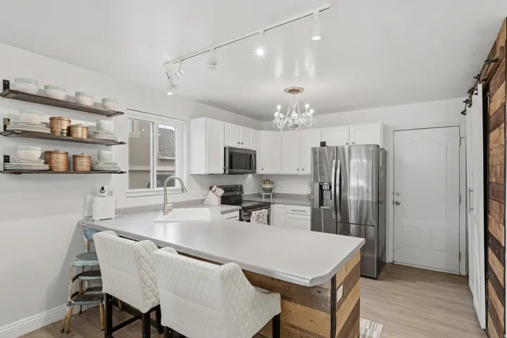 Kitchen featuring white cabinetry, a central island with a wood-finish base, stainless steel appliances, and wood-finish flooring