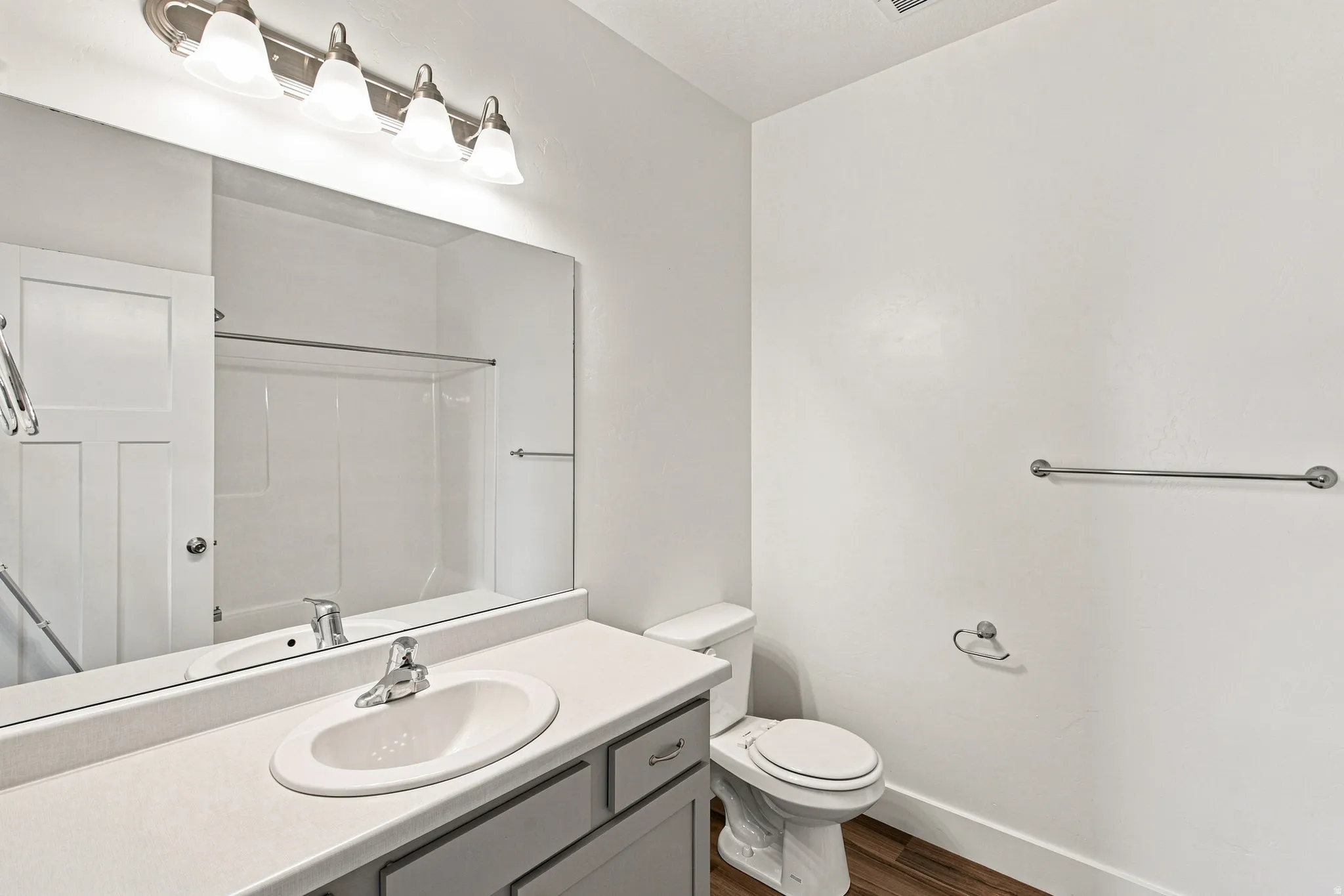 Bathroom featuring a vanity with a single basin sink, brushed nickel faucet, large mirror, and overhead four-light fixture
