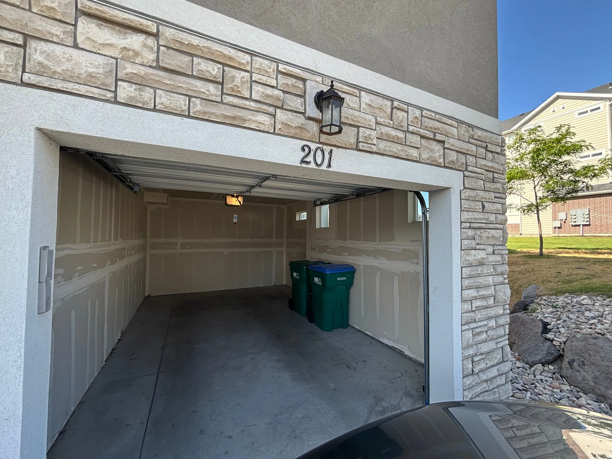 Attached single-car garage featuring a concrete floor, exposed drywall interior, and two small windows for natural light