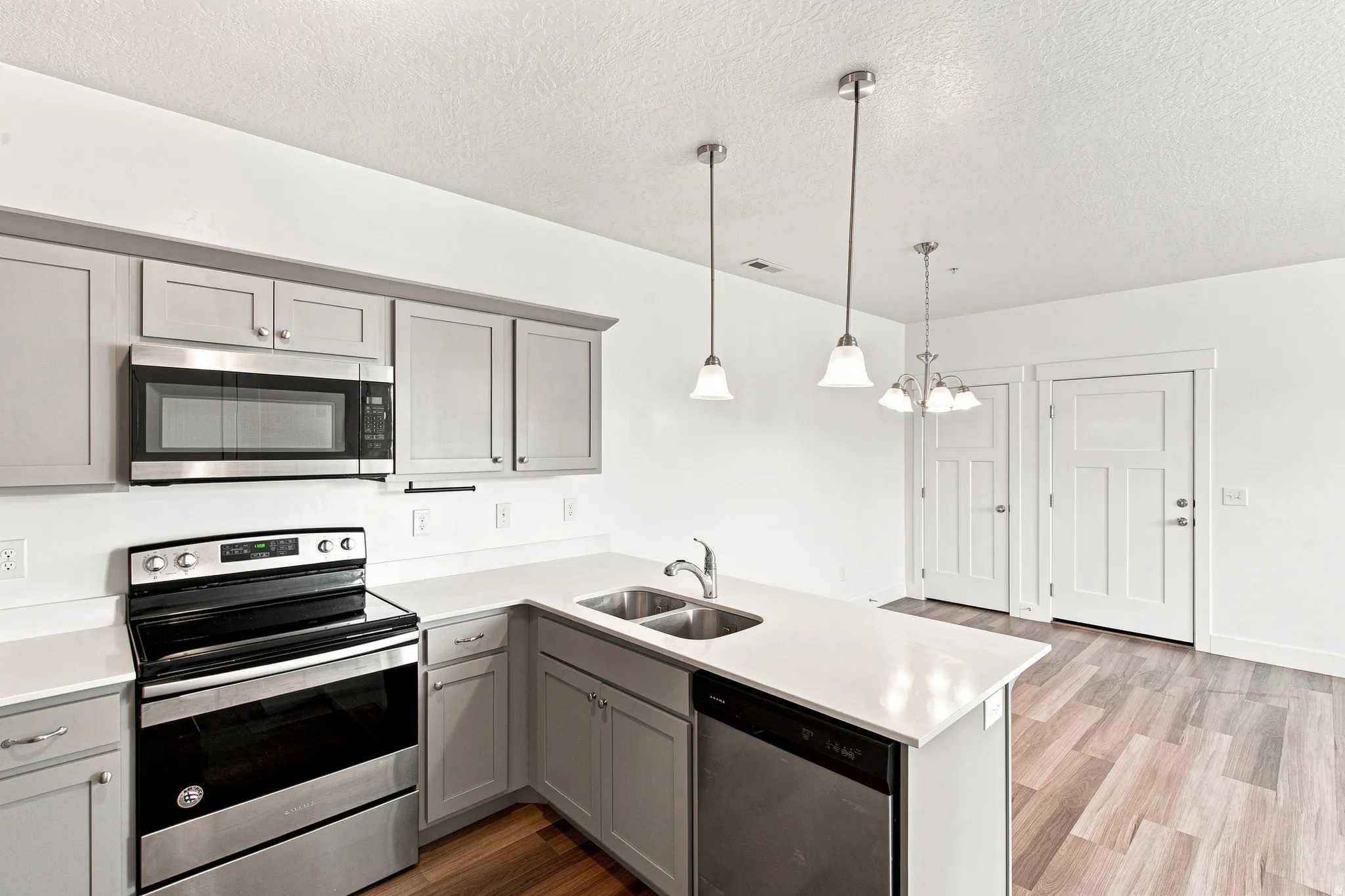 Kitchen featuring light gray cabinetry, stainless steel appliances, and light-toned countertops