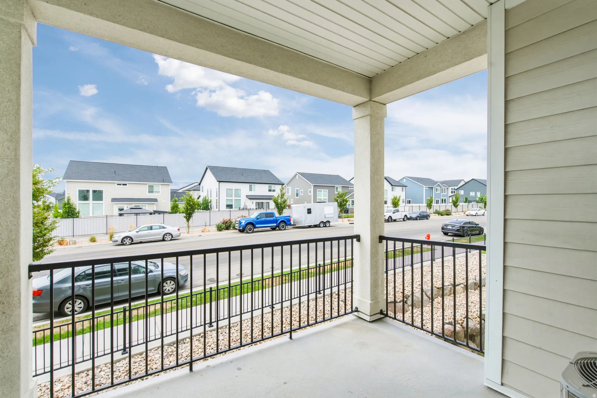 Covered porch with concrete flooring and a black metal railing