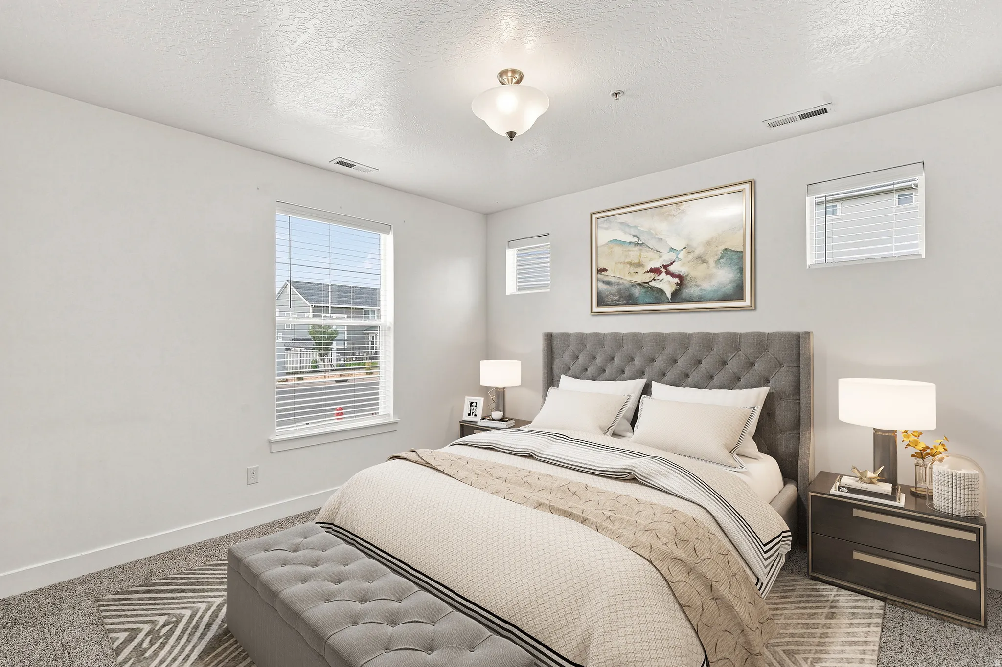 Carpeted room featuring a tufted headboard, multiple windows with blinds, a ceiling-mounted light fixture, and white baseboards