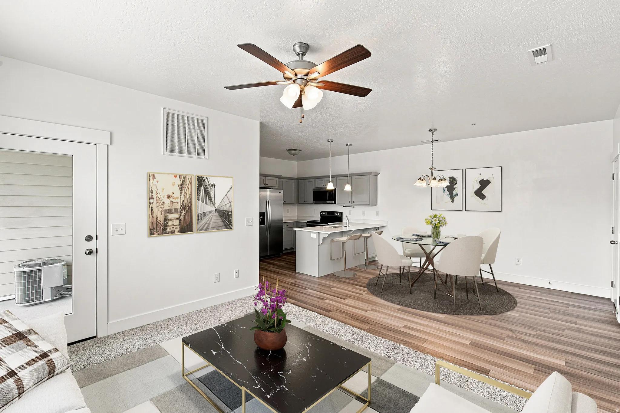 Open-concept living area with wood-finish flooring, a kitchen island with seating, pendant lighting, and a ceiling fan
