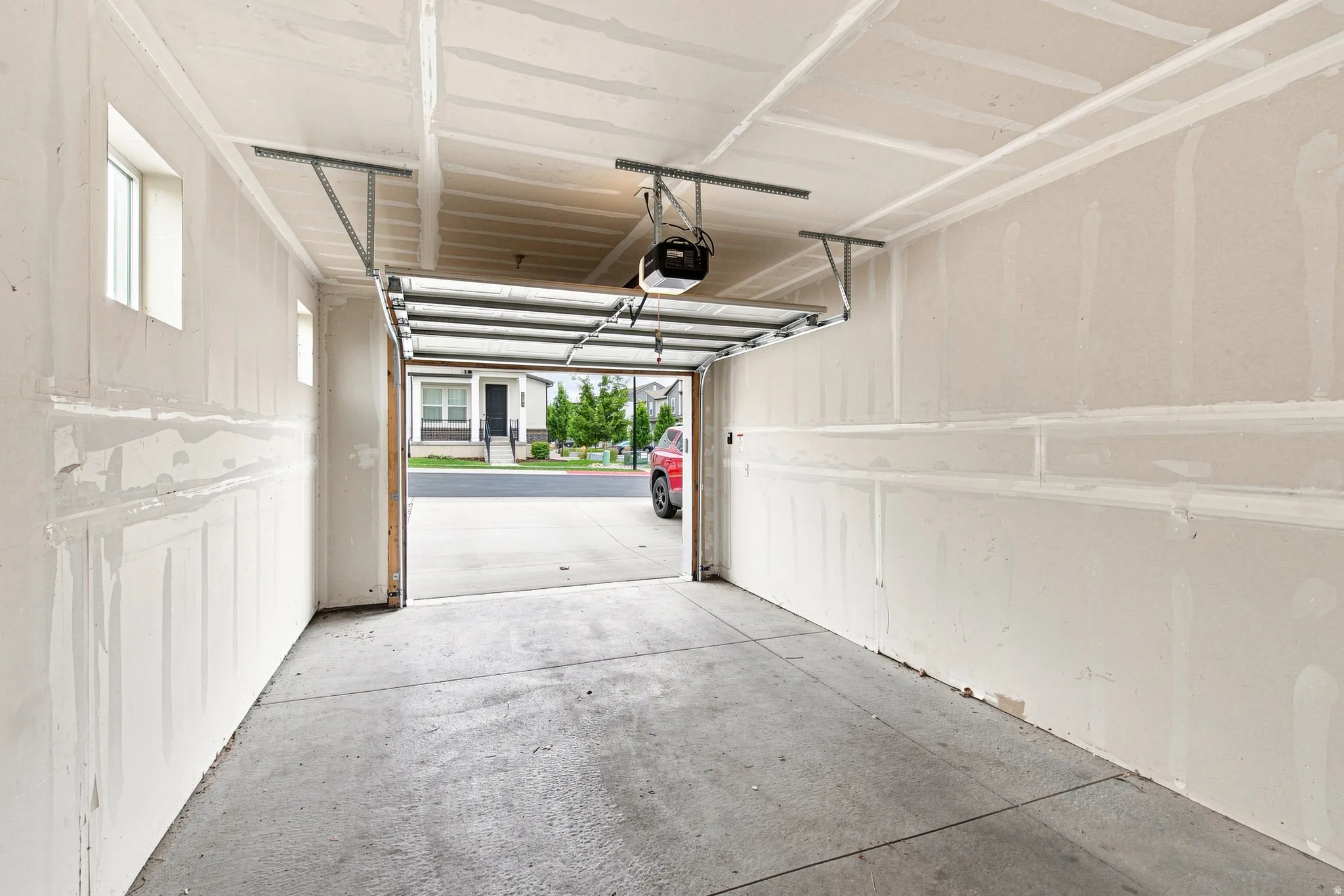 Spacious garage with an automatic overhead door opener, concrete flooring, and multiple windows providing natural light