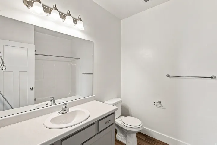 Bathroom featuring a vanity with a single basin sink, brushed nickel faucet, large mirror, and overhead four-light fixture