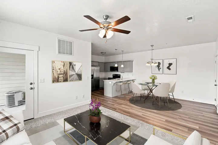 Open-concept living area with wood-finish flooring, a kitchen island with seating, pendant lighting, and a ceiling fan