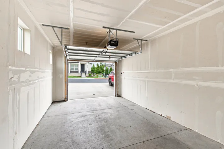Spacious garage with an automatic overhead door opener, concrete flooring, and multiple windows providing natural light
