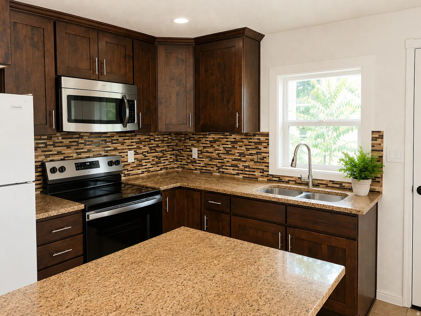 Kitchen featuring dark wood cabinetry, a mosaic tile backsplash, stainless steel appliances, and light-toned countertop surfaces
