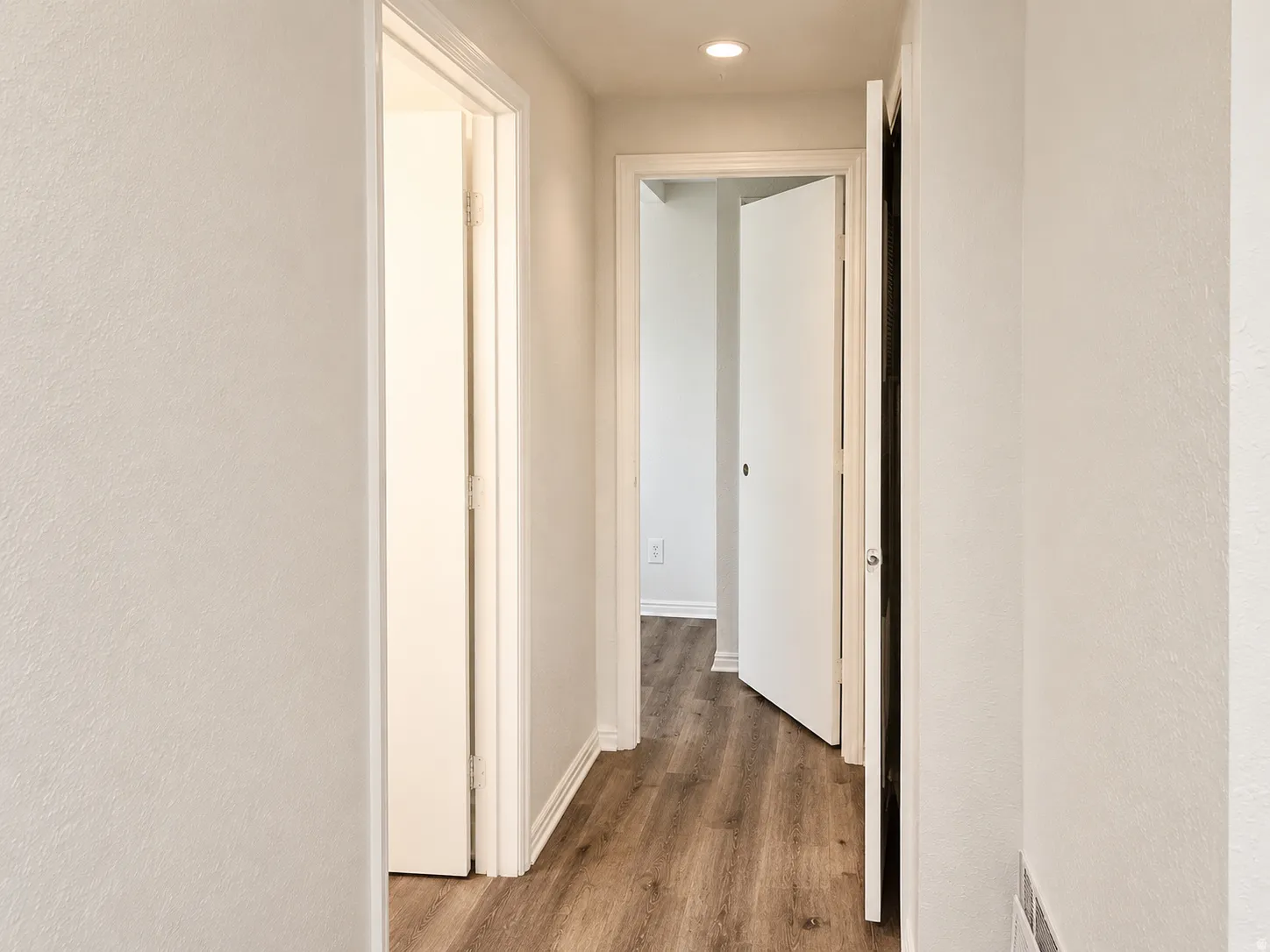 Hallway featuring wood-finish flooring, white baseboards, and recessed lighting