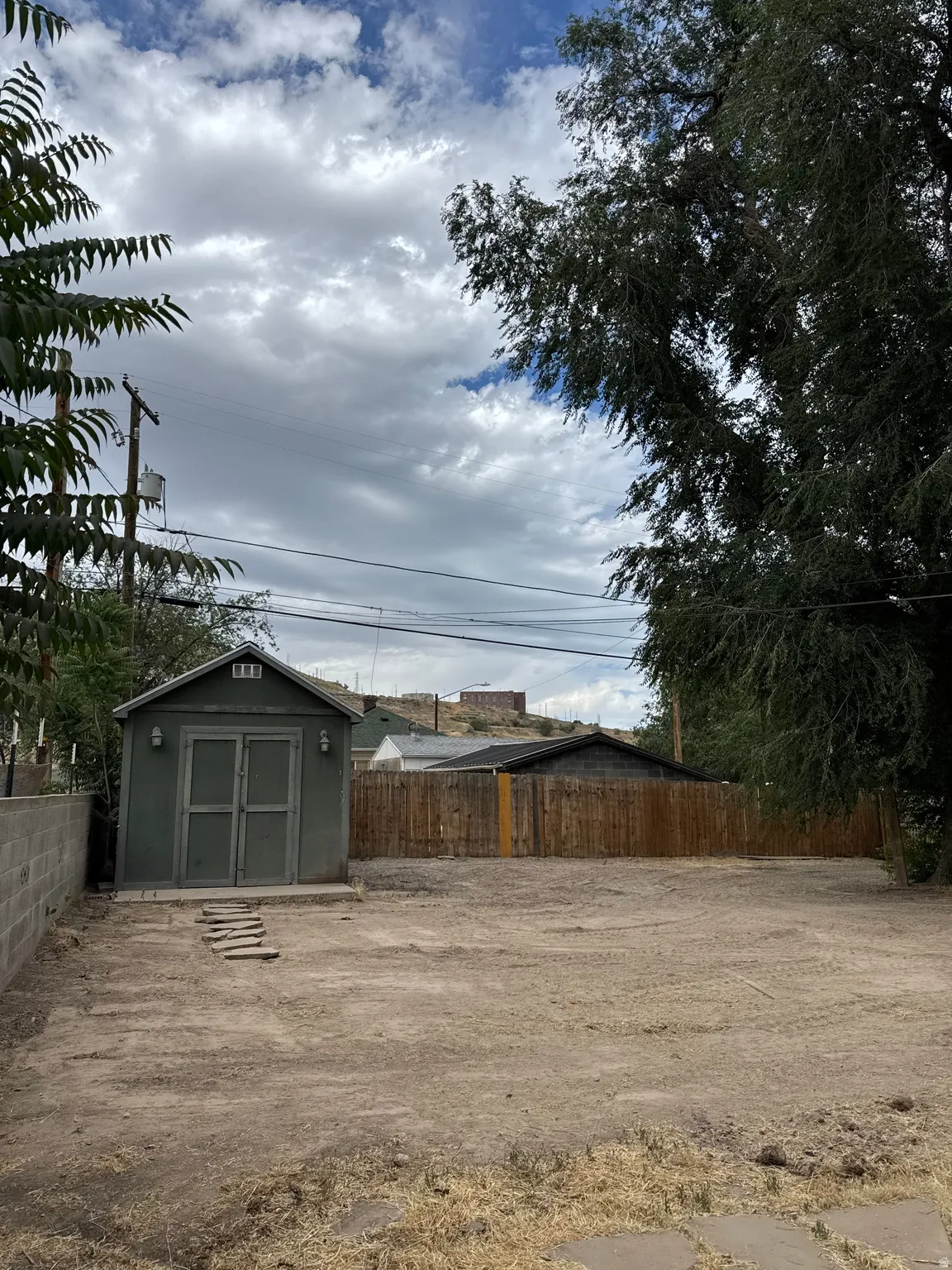 Expansive rear yard featuring a detached storage shed, wood privacy fencing, and a concrete block wall