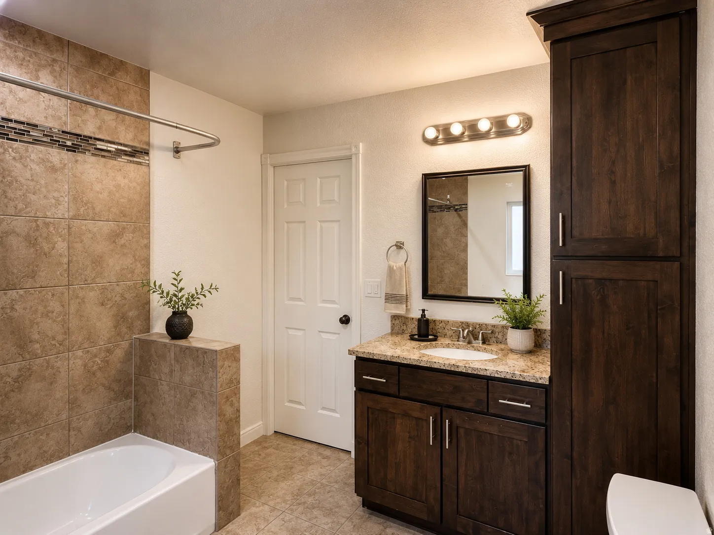 Bathroom featuring a white bathtub with full-height tile surround, a built-in storage cabinet, and a vanity with a granite-style countertop, integrated sink, and dark wood-finish cabinetry