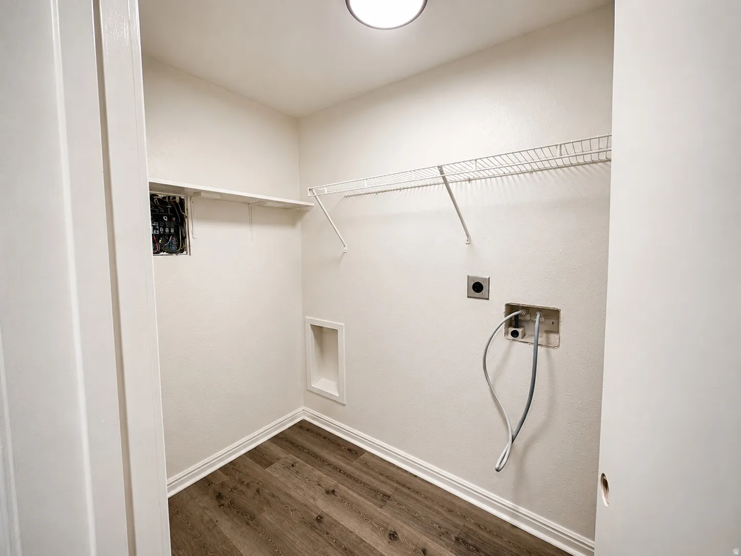 Dedicated utility space featuring wood-finish flooring, white walls, and a recessed ceiling light