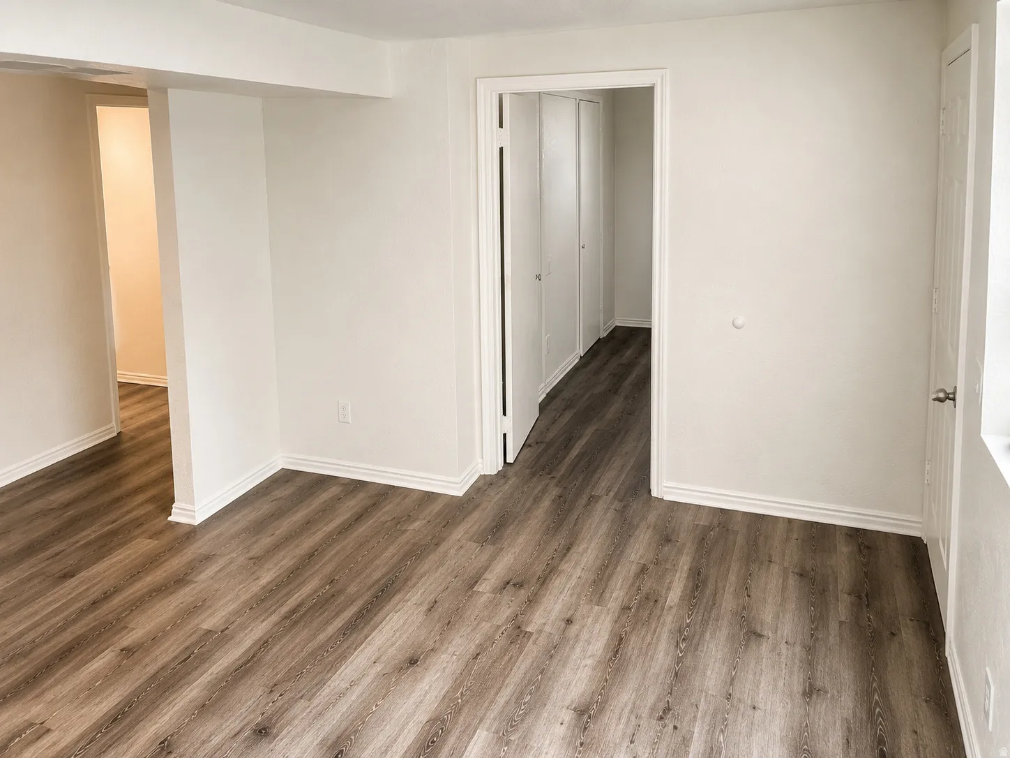 Open interior space featuring wood-finish flooring, white baseboards, and white walls
