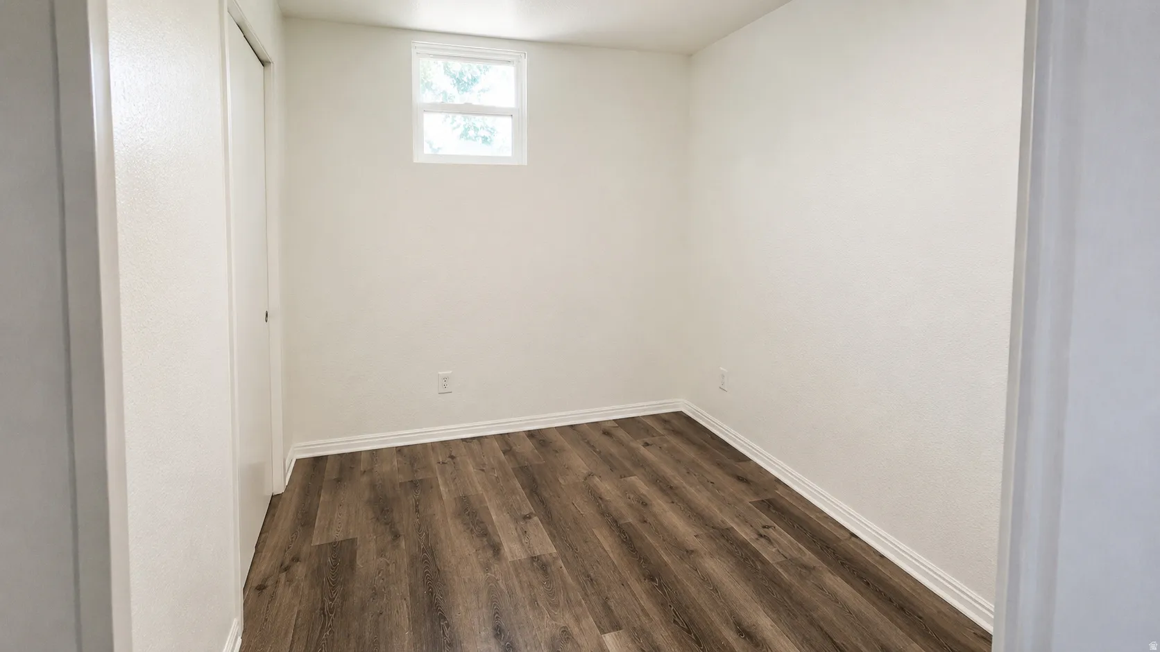 Room featuring wood-finish flooring, white baseboards, and neutral wall paint