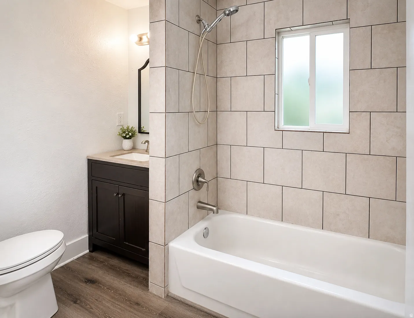 Bathroom featuring a white bathtub, tiled shower surround, and a frosted window