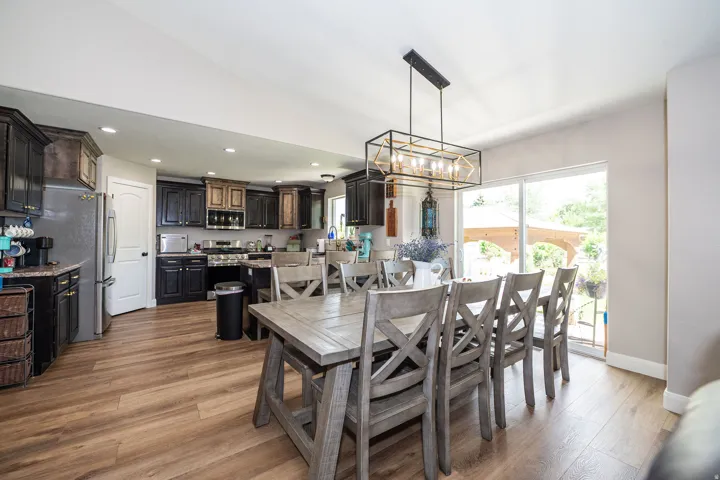 Open-concept kitchen and dining area featuring wood-finish flooring, recessed lighting, and a modern rectangular chandelier