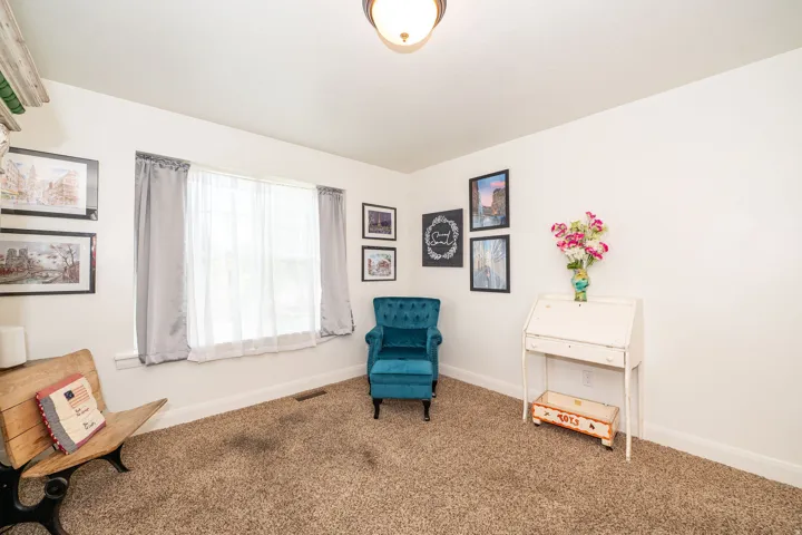 Carpeted room featuring a ceiling-mounted light fixture, white walls, and a window with sheer and blackout curtains