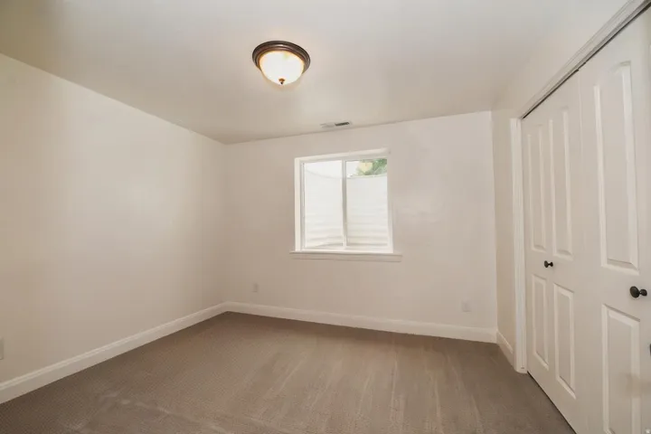 Carpeted room featuring a white-trimmed window, white baseboards, and a bronze-finish flush mount ceiling light