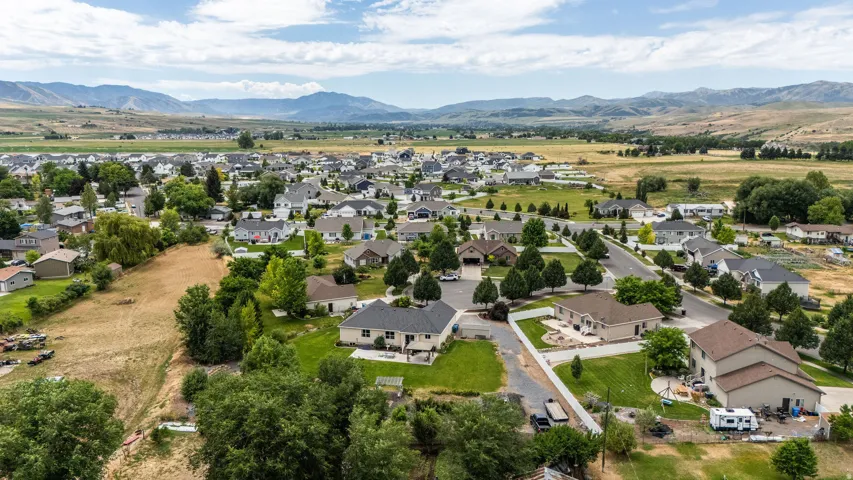 Residential neighborhood featuring single-family homes, mature landscaping, paved streets, and mountainous terrain in the distance