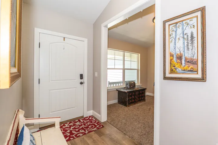 Entryway featuring wood-finish flooring, a white paneled door with dark hardware, and neutral wall paint
