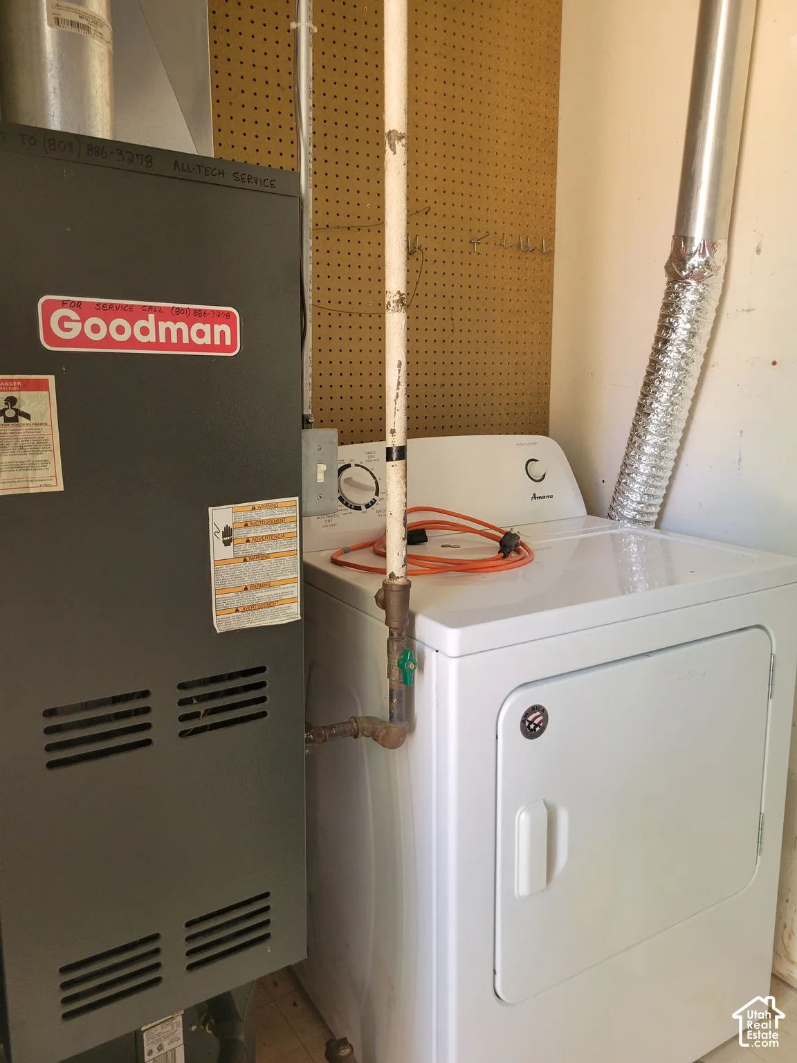 Dedicated laundry area featuring a white electric dryer and adjacent furnace unit