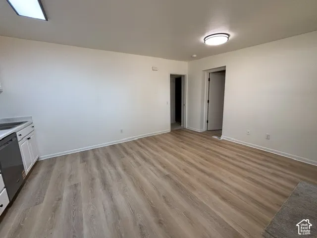 Wood-finish flooring, white cabinetry, dark hardware, and light countertops