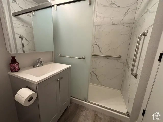 Shower with frosted glass sliding door, white shower base, and marble-patterned wall tile