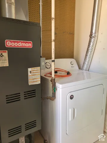 Dedicated laundry area featuring a white electric dryer and adjacent furnace unit
