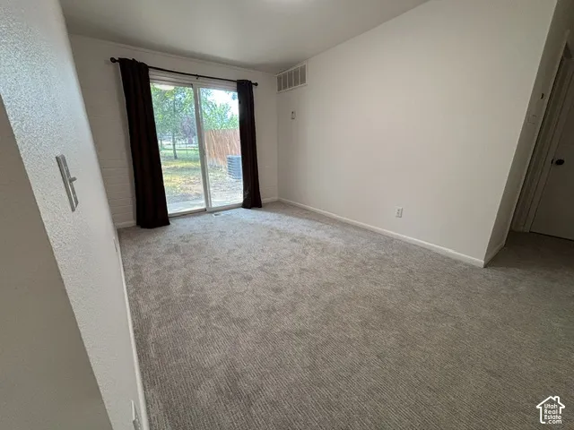 Sliding glass door leading to exterior, light gray textured carpet, white painted walls, and white ceiling