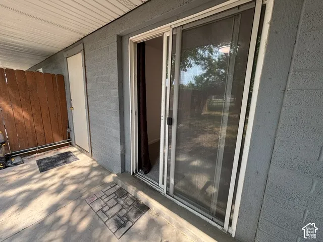 Private patio area with concrete flooring, a sliding glass door, and a privacy fence