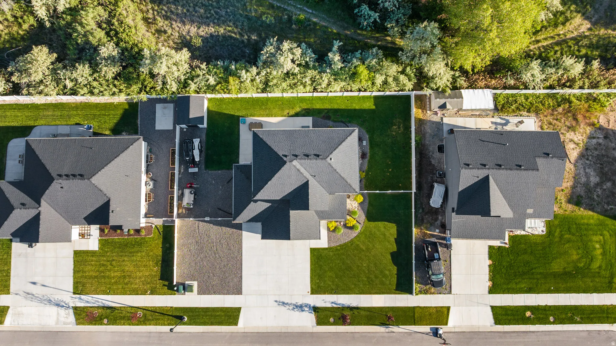 Central property featuring a dark shingle roof, concrete driveway, and a verdant lawn