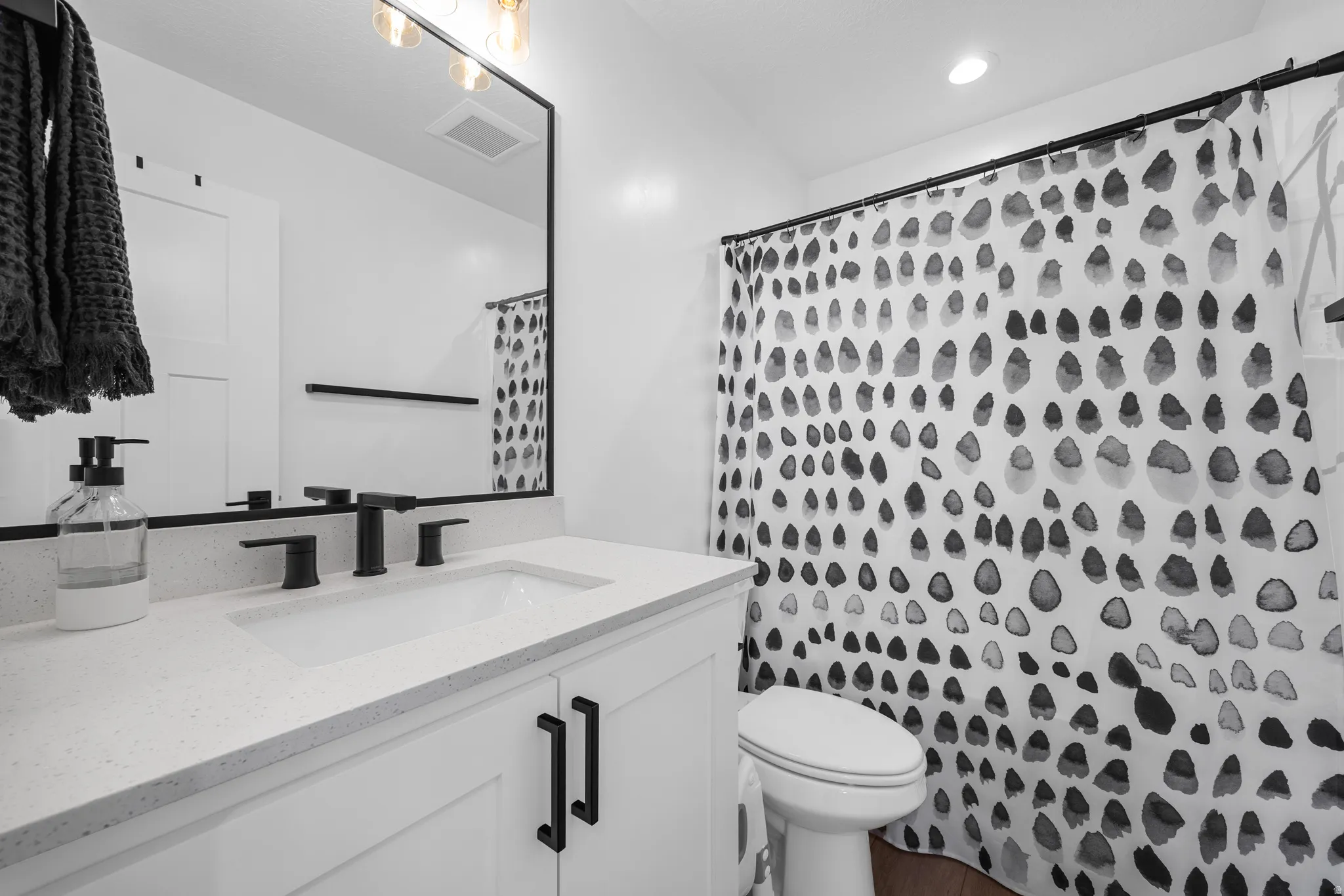 Bathroom featuring a white vanity with an integrated sink, matte black faucet, and a large black-framed mirror
