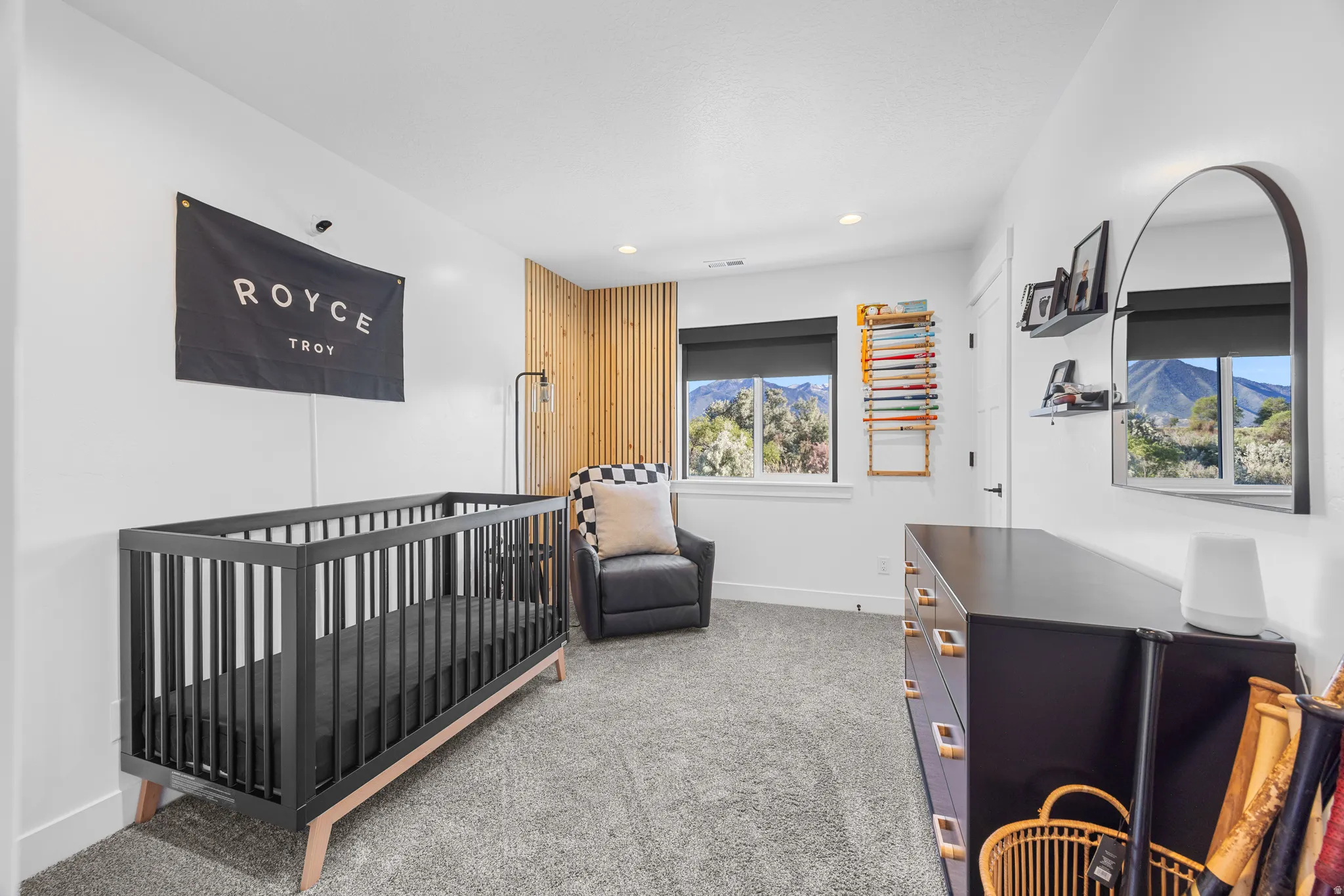 Interior room featuring light gray carpet flooring, white walls, and a wood-slat accent wall