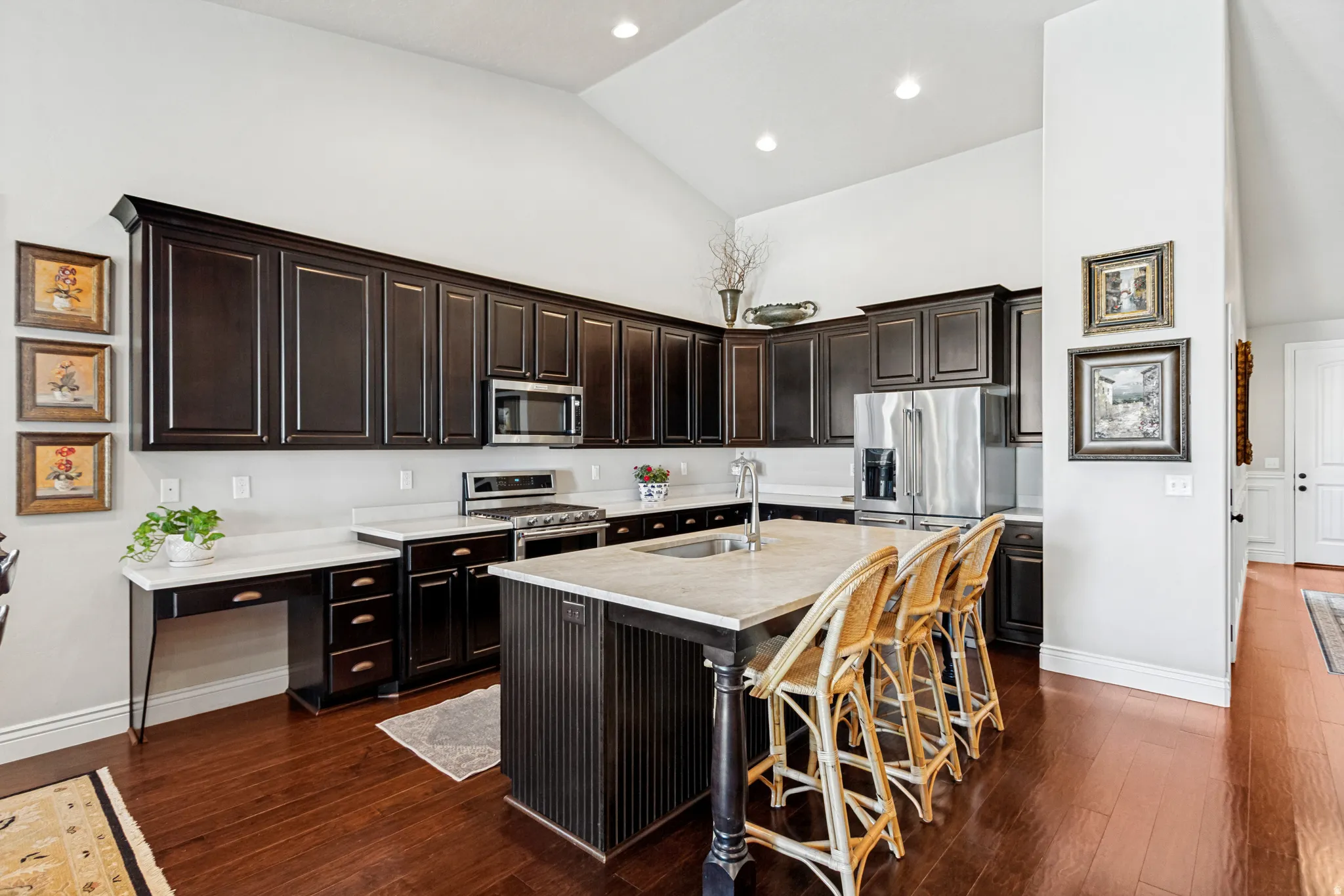 Kitchen featuring dark wood cabinetry, light-toned countertops, stainless steel appliances, and wood-finish flooring
