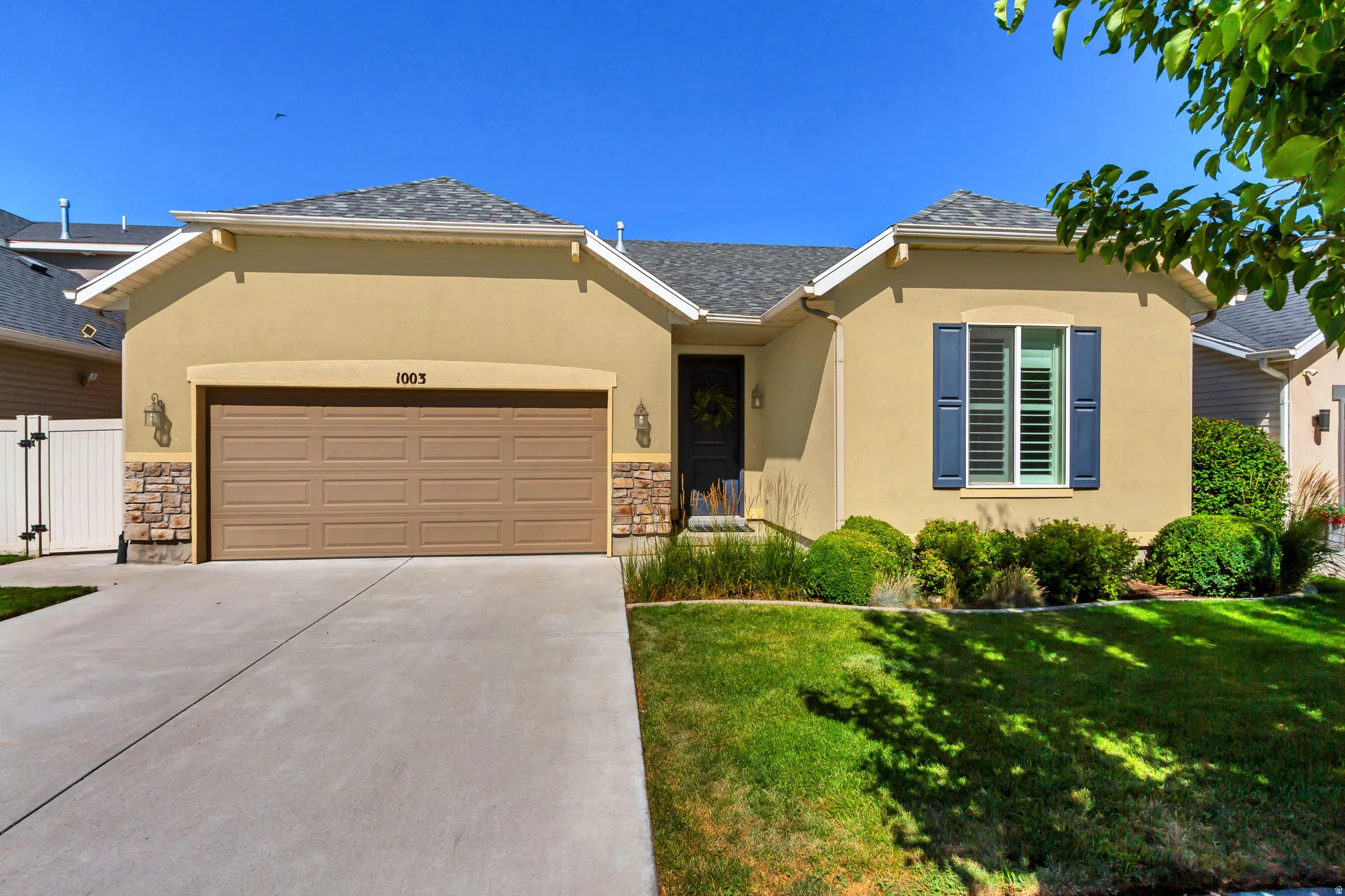 Stucco exterior residence featuring a two-car garage with an automatic door, stone accents, and a covered entry