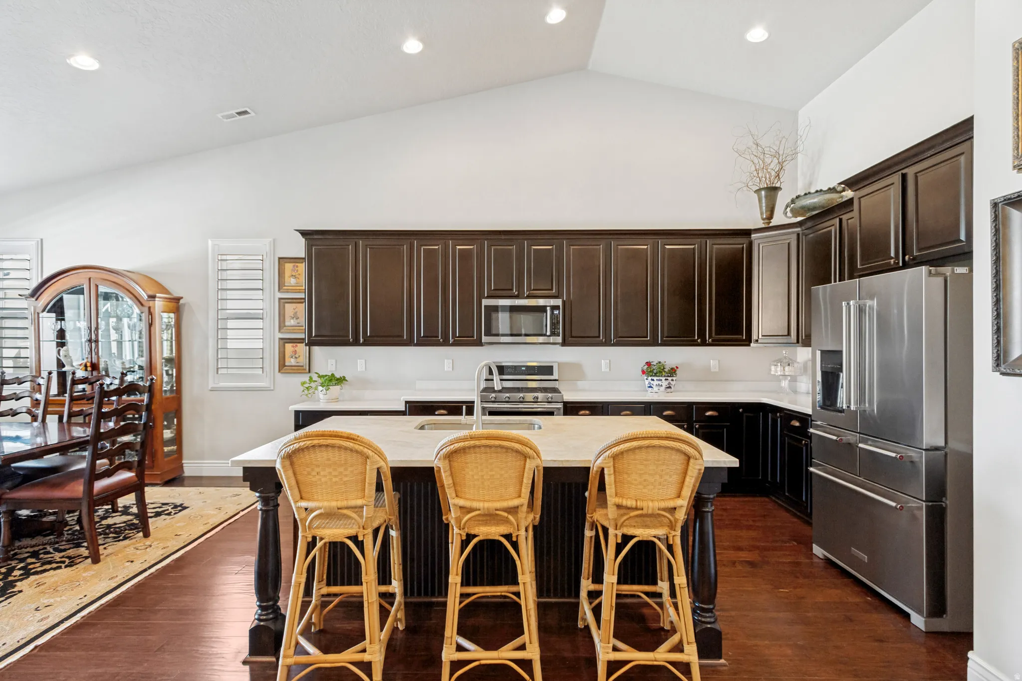Kitchen featuring dark wood cabinetry, stainless steel appliances, a center island with countertop seating, and recessed lighting