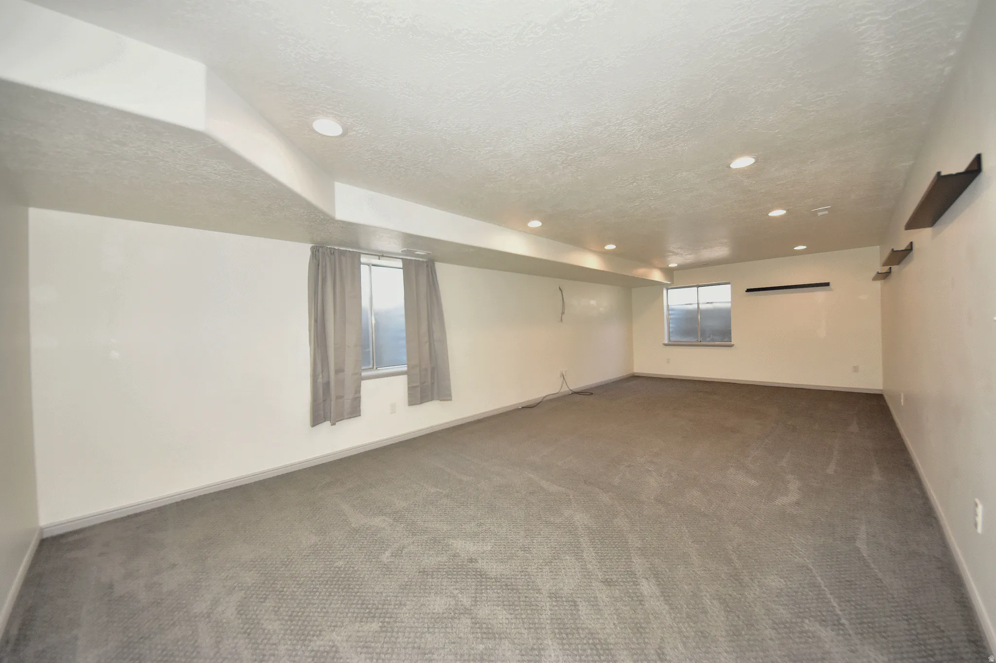 Spacious room featuring neutral carpeting, recessed lighting, multiple windows, and light-toned walls