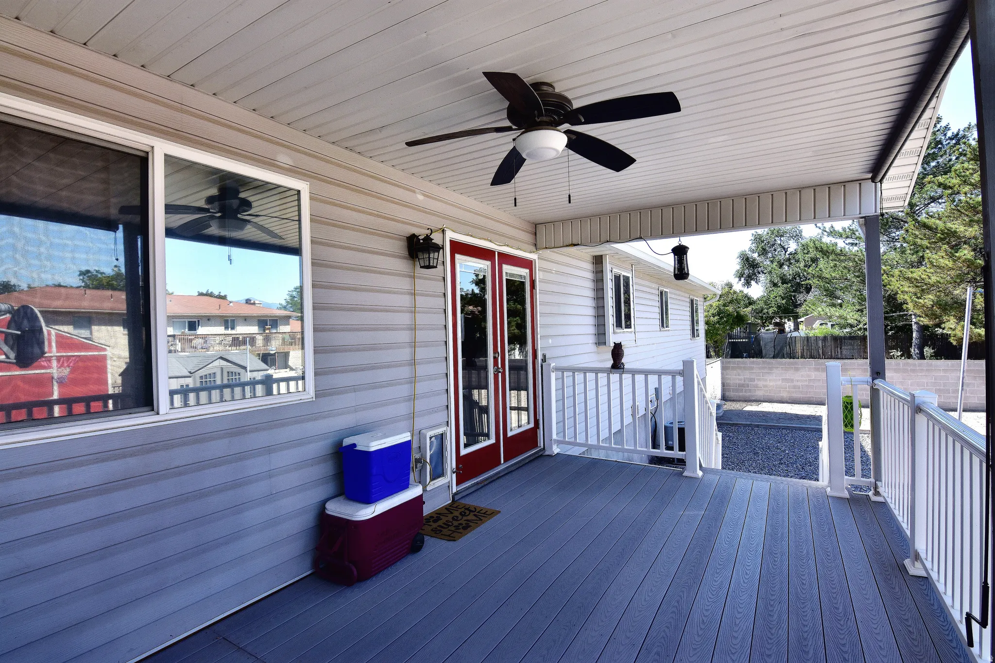 Covered outdoor deck featuring composite decking, white railing, and a ceiling fan