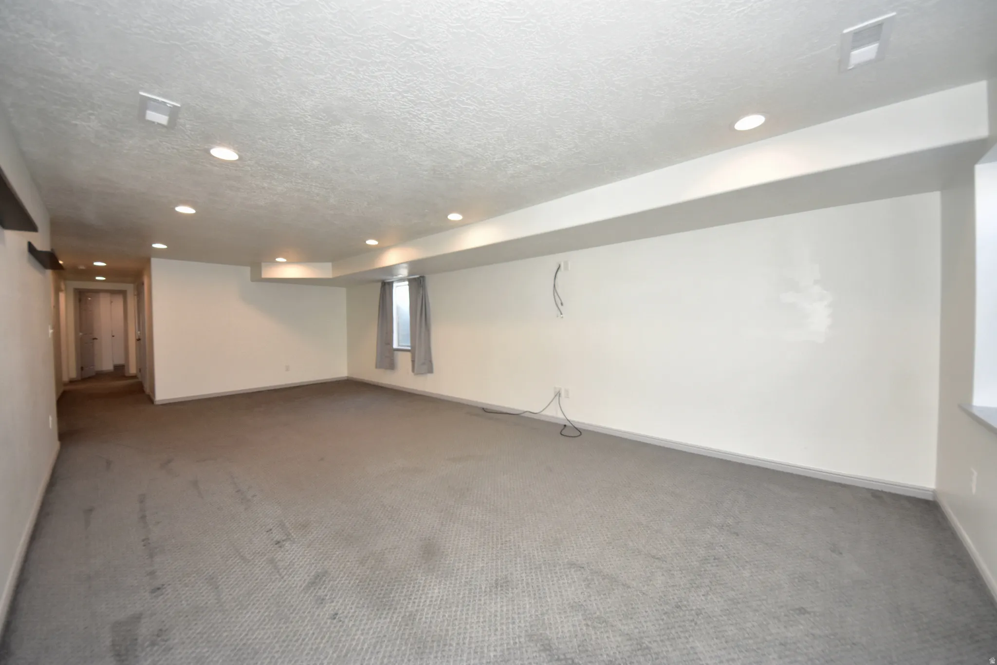 Spacious room featuring neutral carpeting and recessed lighting