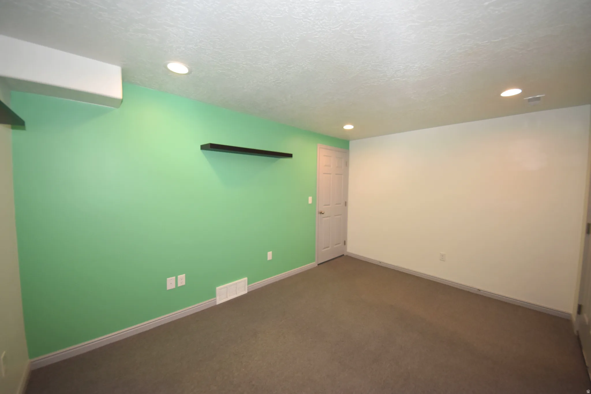 Spacious room featuring accent wall, recessed lighting, neutral carpeting, and white trim