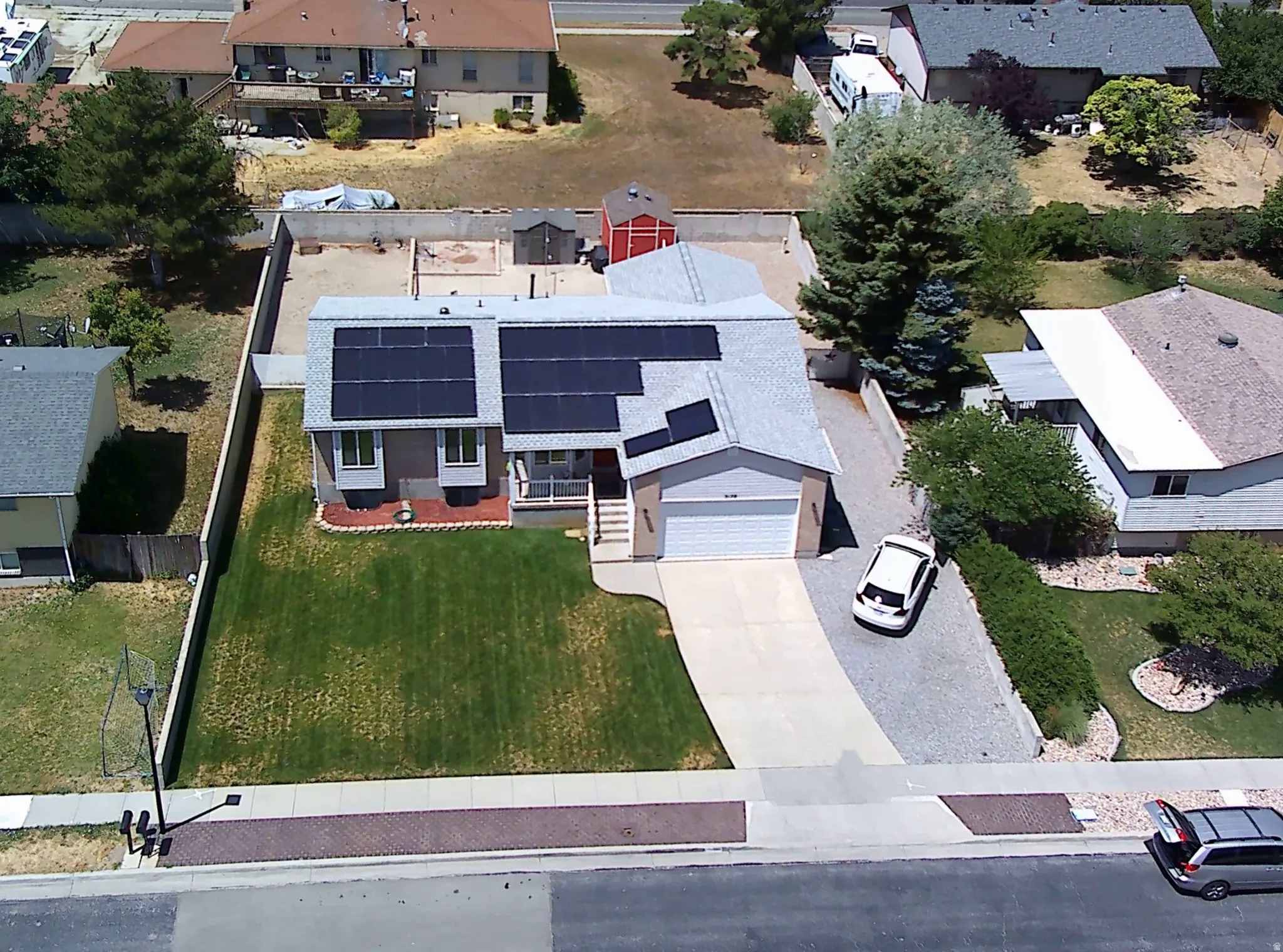Ranch-style residence featuring solar panels, an attached two-car garage, and a concrete driveway
