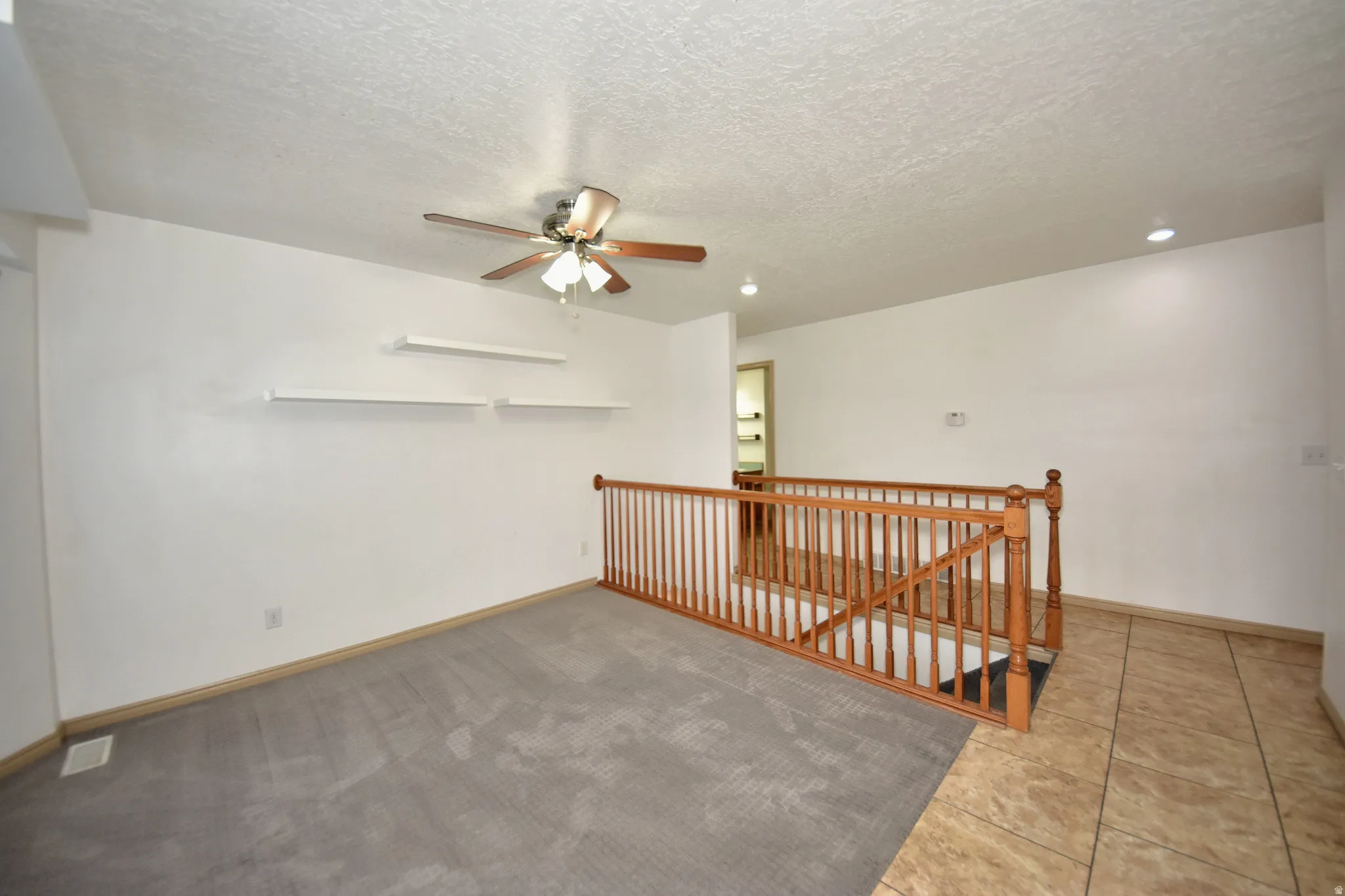 Open concept living area with light gray carpet and ceramic tile flooring